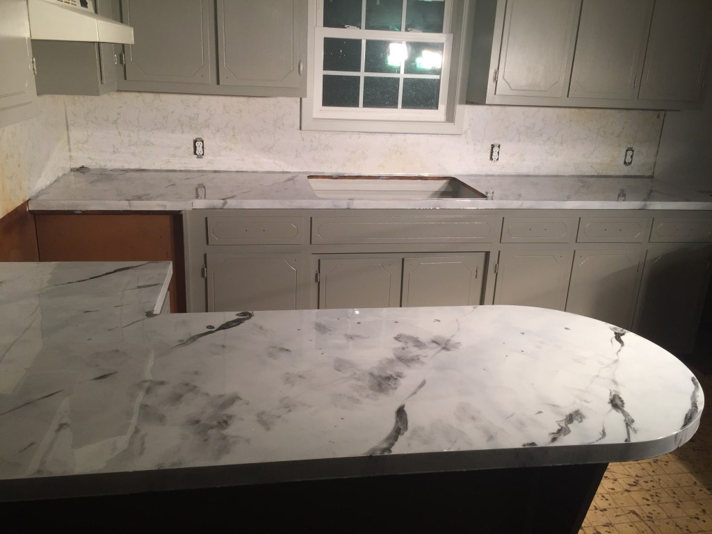 Same kitchen counters refinished in a white marble-look finish with gray veining